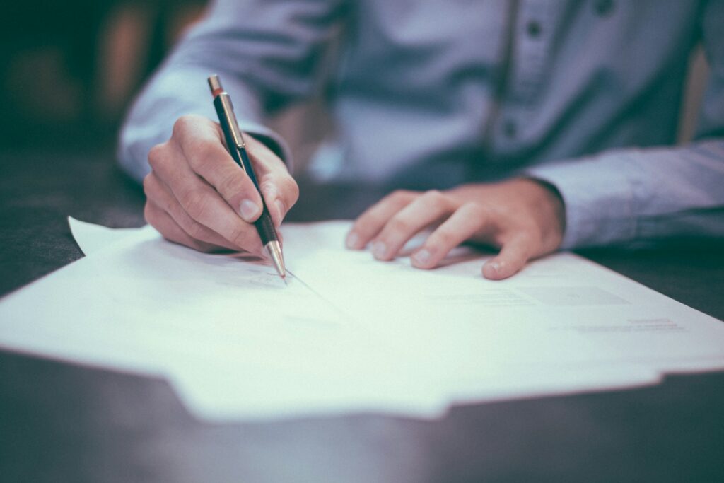 Close-up of a person signing an official document with a pen, symbolizing legal certification, notarization, or document verification.